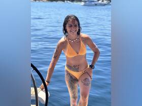 A joyful woman poses on the steps of a boat, enjoying a sunny day on the water — perfect for summer adventures and beach outings.