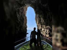 A couple enjoys a stunning view from their boat inside a cave, capturing a perfect moment of adventure and romance on the water.