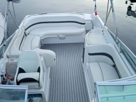 A spacious interior view of a boat's seating area, featuring comfortable lounge spaces and a helm, perfect for relaxing on the water.