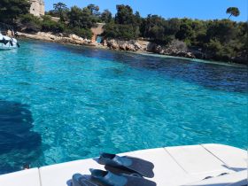 A pair of snorkel fins rests on the edge of a boat, overlooking the stunningly clear turquoise waters, perfect for underwater exploration.