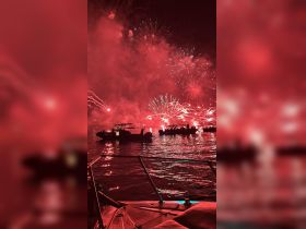 A stunning display of fireworks lights up the night sky, viewed from a boat surrounded by fellow revelers — a perfect scene for festive celebrations on the water.