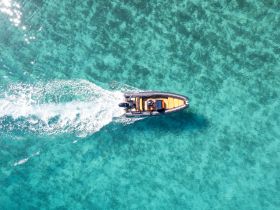 Aerial view of a sleek speedboat cruising through crystal-clear turquoise waters, showcasing the perfect day for adventure on the sea.