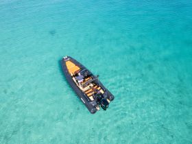 Aerial view of a sleek speedboat cruising through crystal-clear turquoise waters, perfect for exploring coastal destinations.