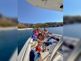 A lively group of friends enjoys a fun day on a pontoon boat, capturing memories against a stunning coastal backdrop — perfect for group outings and celebrations.