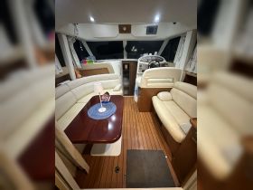 A cozy interior view of a boat cabin featuring comfortable seating and a well-equipped helm, perfect for relaxing or navigating on the water.