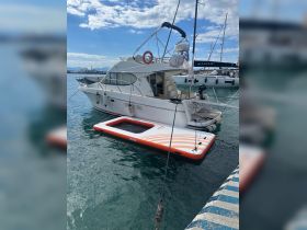 A sleek yacht docked at the marina, showcasing its elegant design and a floating mat nearby, perfect for relaxation on the water.
