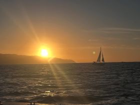 A serene sunset view featuring a sailboat gracefully navigating the waters, creating a picturesque scene perfect for sailing enthusiasts.