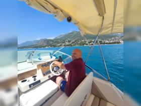 A cheerful captain navigates a boat on clear blue waters, showcasing the joy of a day out on the sea.