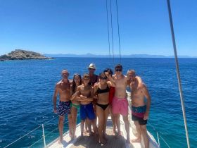 A joyful group of family and friends poses on the deck of a yacht, enjoying a sunny day on the water — perfect for memorable summer adventures.
