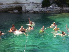 A lively group enjoys a refreshing swim in crystal-clear waters, perfect for summer fun and beach outings.