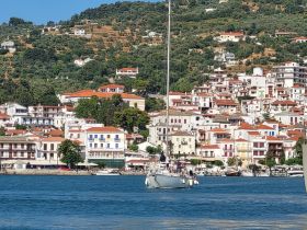A picturesque view of a sailboat navigating through a vibrant harbor, with charming coastal buildings in the background — a perfect representation of sailing adventures in scenic destinations.