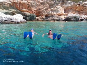 Two snorkelers enjoy the crystal-clear waters near a rocky coastline, showcasing the beauty of underwater adventures.