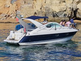 A group of friends enjoys a day on the water aboard a Fairline Targa 34, with stunning coastal scenery in the background.