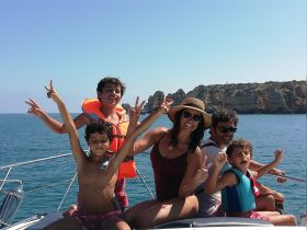A joyful family poses on the bow of a boat, enjoying a sunny day on the ocean — perfect for creating lasting memories together.
