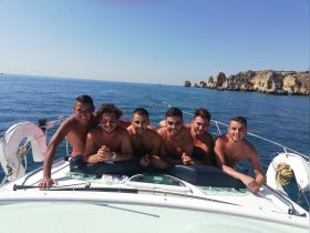 A group of friends enjoys a sunny day on the boat, capturing a moment of fun and camaraderie against a stunning ocean backdrop.