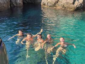 A joyful group of friends enjoys a refreshing swim in crystal-clear waters, perfect for snorkeling adventures and summer fun.