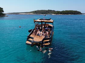 A lively group enjoys a fun day on a boat in stunning turquoise waters, with some swimming and others relaxing on deck — perfect for summer adventures.