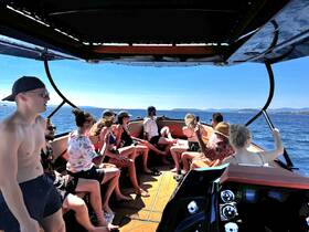 A lively group enjoys a sunny day on a boat, capturing memories and having fun on the water — perfect for social gatherings and celebrations.