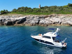 A group enjoys a sunny day aboard a boat near a picturesque coastline, perfect for swimming and relaxation.