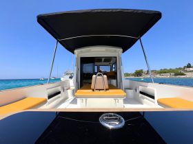 Interior view of a modern boat cabin featuring comfortable seating and a sleek helm, perfect for relaxing on the water.