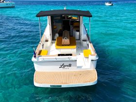 A stunning view of the Loreta yacht anchored in crystal-clear waters, showcasing its sleek design and inviting seating area — perfect for a day of relaxation on the water.