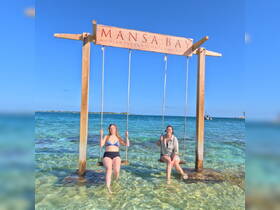 Two friends enjoy a sunny day swinging in the shallow waters of Mansa Bay, capturing the essence of fun and relaxation in a tropical paradise.
