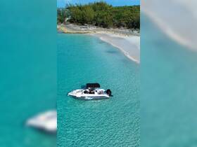 A stunning aerial view of a sleek speedboat anchored in crystal-clear turquoise waters, perfect for exploring the beautiful coastline and enjoying water activities.