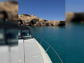 A stunning view of a boat's exterior with rocky cliffs in the background, showcasing the serene turquoise waters — perfect for exploring coastal landscapes.