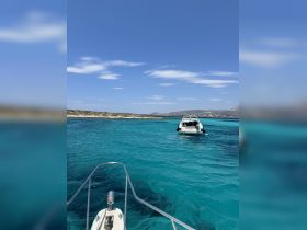 A stunning view of a boat navigating through crystal-clear turquoise waters, showcasing the beauty of a sunny day on the water.