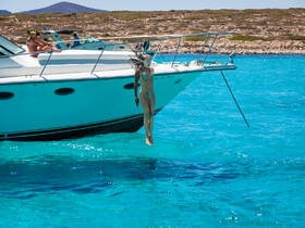 A woman jumps into the crystal-clear waters from the side of a boat, capturing the essence of summer fun and adventure on the water.