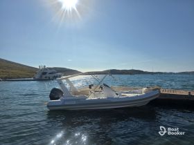 A sleek speedboat docked in calm waters, with a picturesque backdrop of hills and a larger yacht in the distance, perfect for exploring coastal destinations.