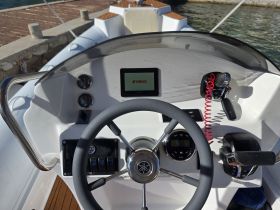 A detailed view of the helm and console of a boat, showcasing the steering wheel and control panel, ideal for navigation and boating enthusiasts.
