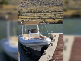A sleek speedboat docked at a serene waterfront, showcasing its elegant design against a backdrop of rocky terrain.
