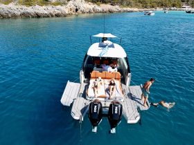 A lively group enjoys a sunny day on a luxury boat, with some swimming and others sunbathing — the perfect setting for a fun-filled day on the water.