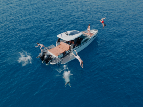 A lively group enjoys a fun day on the water, jumping off the boat into the clear blue sea — perfect for summer adventures and water activities.