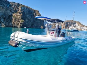 A sleek speedboat navigates through crystal-clear waters, showcasing the stunning coastal cliffs in the background — perfect for diving adventures or scenic tours.
