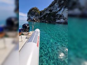 A sleek boat glides through crystal-clear waters, showcasing stunning rock formations in the background — perfect for exploring coastal destinations.