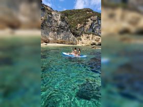 A couple enjoys paddleboarding in crystal-clear waters near a scenic beach, perfect for adventurous outings and exploring coastal beauty.