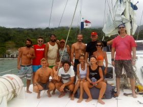 A lively group of friends poses together on a sailboat, capturing the joy of their sailing adventure — perfect for memorable trips and celebrations on the water.
