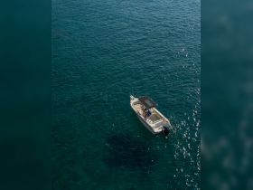 Aerial view of a speedboat cruising through clear turquoise waters, showcasing the vessel's sleek design and perfect for water adventures.