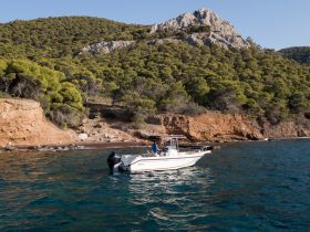 A speedboat navigates the clear waters near a rocky coastline, showcasing the beauty of the natural landscape — perfect for exploring secluded beaches.