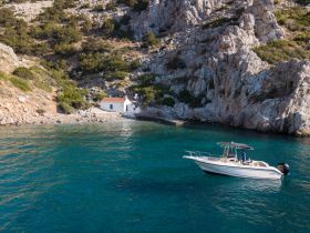 A scenic view of a boat navigating along a rocky coastline, showcasing the beauty of the landscape and the adventure of exploring hidden coves.