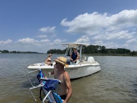 A group enjoys a sunny day on the water, relaxing on a boat with drinks in hand — perfect for summer outings and fun on the water.