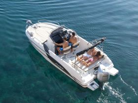 A group enjoys a sunny day on a boat, with one person at the helm and others relaxing on the deck — a perfect scene for summer adventures on the water.