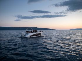 A lively group enjoys a scenic boat ride at sunset, creating the perfect backdrop for memorable moments on the water.