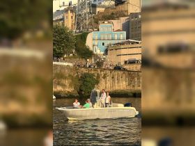 A group of friends enjoys a scenic boat ride along the waterfront, with vibrant city buildings in the background, perfect for capturing memorable moments on the water.