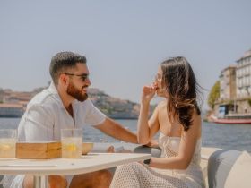 A couple enjoys drinks and laughter on a sunny boat trip, capturing the essence of romance and relaxation on the water.