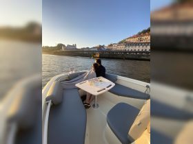 A couple enjoys a romantic moment on a boat at sunset, sipping drinks and taking in the scenic views — perfect for intimate outings or special celebrations.