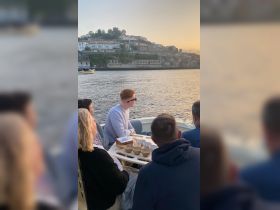 A group of friends enjoys a sunset boat ride, sharing a meal and drinks while taking in the scenic views along the waterfront.