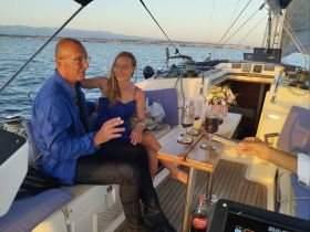 A couple enjoys cocktails on a yacht, celebrating against a stunning sunset backdrop — perfect for romantic getaways or special occasions on the water.